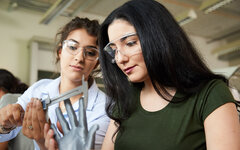 Zwei junge Frauen betrachten eine Hand aus Plastik.