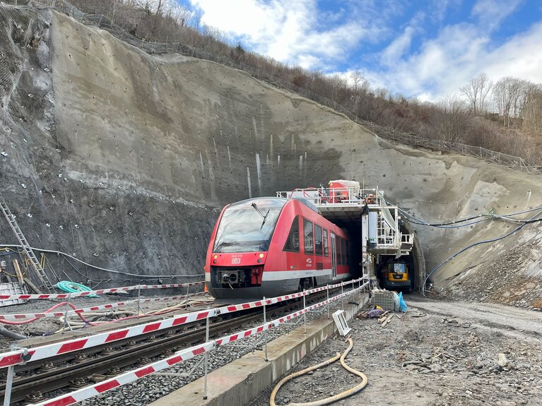 Ein Zug fährt durch einen Tunnel, an dem gearbeitet wird.