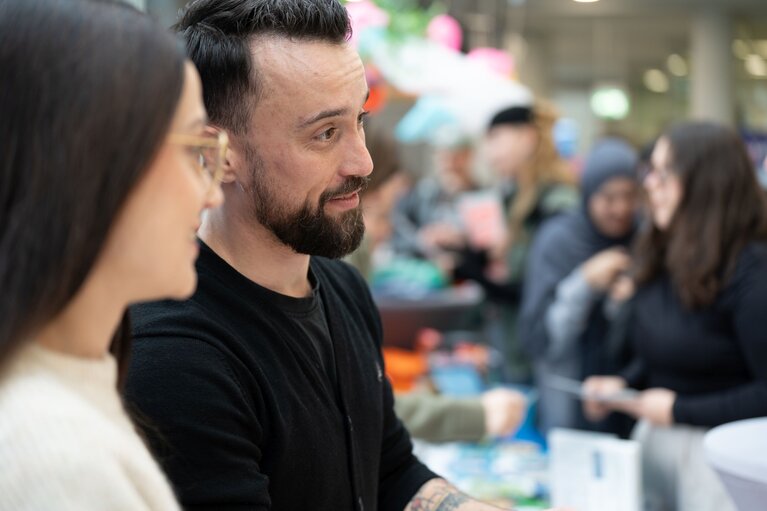 Eine Frau und ein Mann und Teilnehmende im Hintergrund.