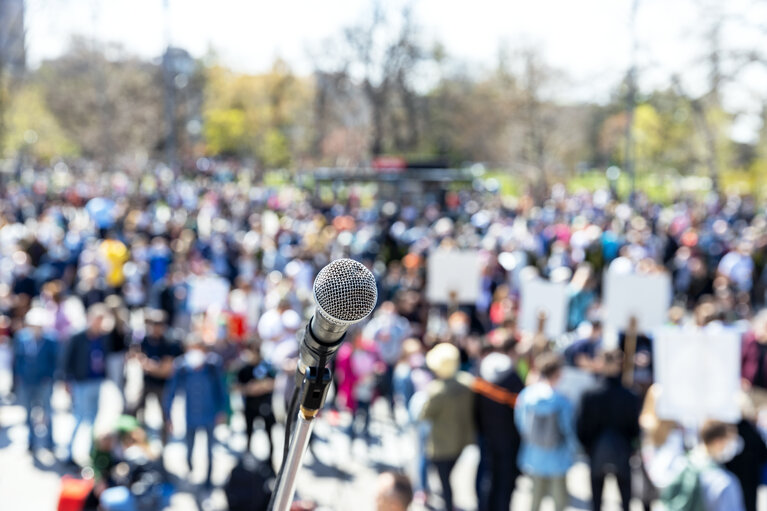 Blurred group of people at protest or public demonstration, focus on microphone