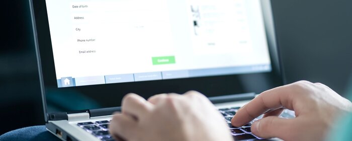 Hände an der Tastatur eines Laptops mit Anmeldemaske
