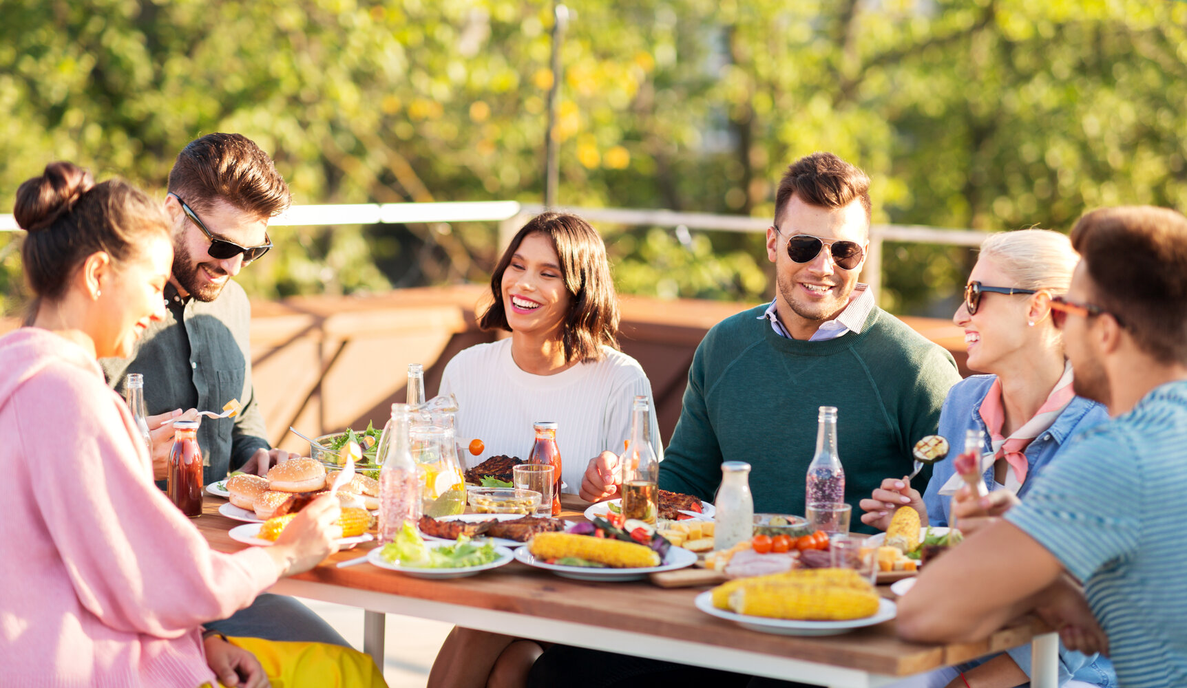 happy friends eating and drinking at rooftop party