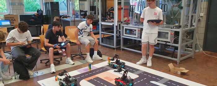 Vier Jungen mit programmierten Fahrzeugen im Labor