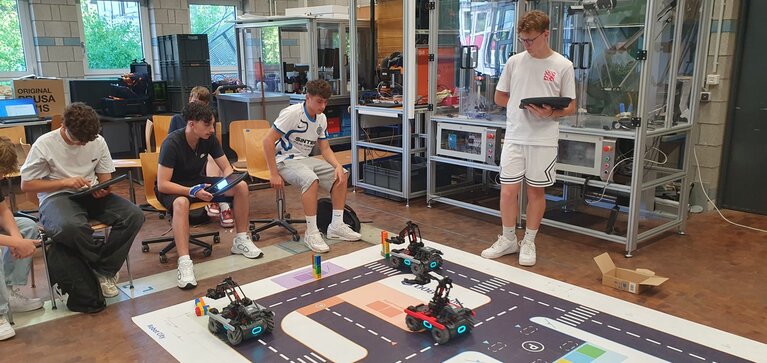Vier Jungen mit programmierten Fahrzeugen im Labor