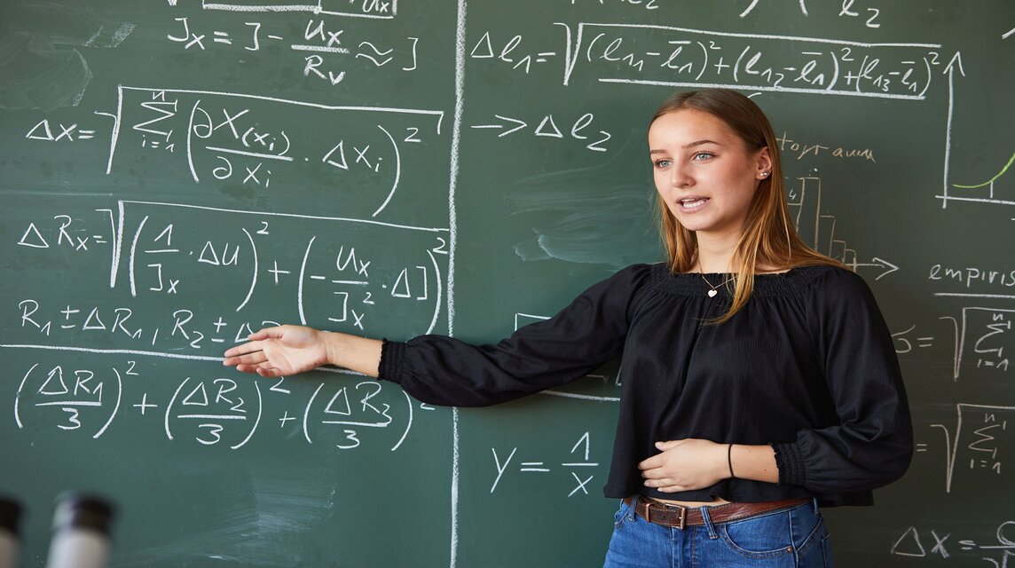 Studentin vor der Tafel mit mathematischen Formeln