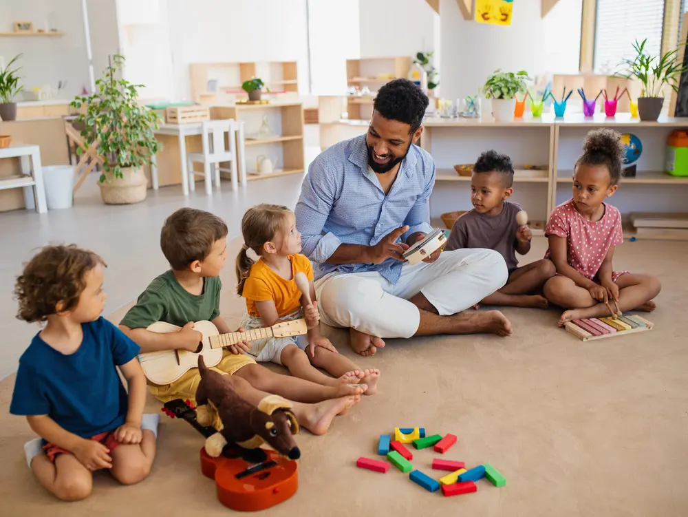 Spielkreis mit Kindern und einem Mann.