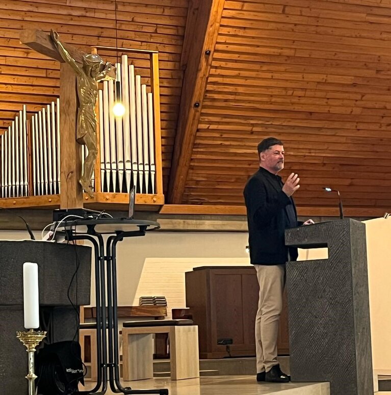 Ein Mann steht am Rednerpult in einer Kirche.