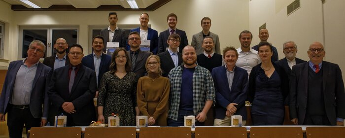 Eine Gruppe von Absolvierenden steht mit den Professoren und der Professorin zusammen.