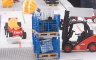 Spielzeug eines Staplers, welcher eine Palettenbox auf eine andere absetzt.