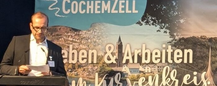 EIn Mann steht als Moderator auf der Bühne.