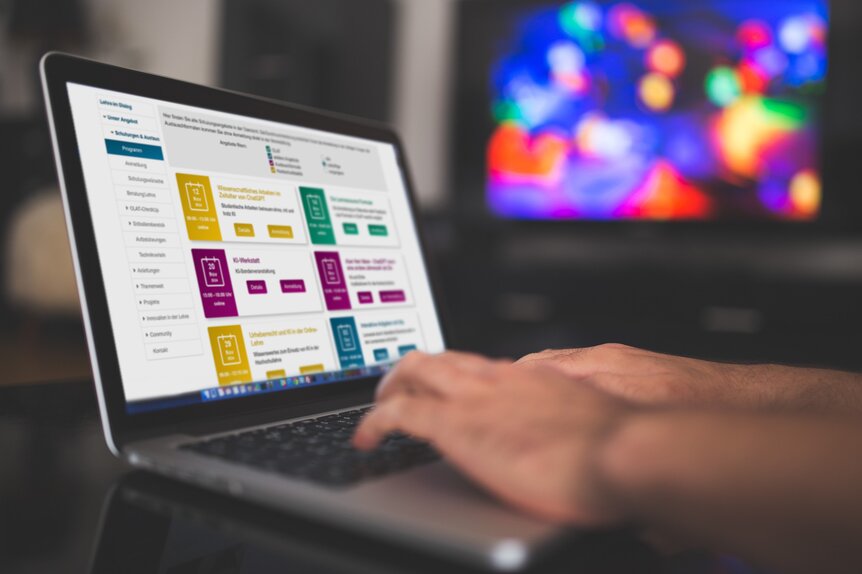 Das Bild zeigt einen Laptop auf einem Tisch. Die Hände einer Person reichen von außerhalb des Bildausschnitts auf die Tastatur. Auf dem Bildschirm ist das geöffnete Schulungsprogramm des E-Learning-Portals zu erkennen.