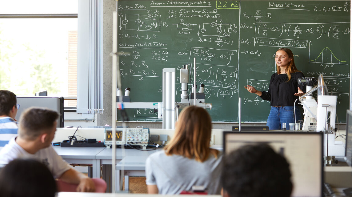 Studentin an der Tafel vor mathematischen Formeln