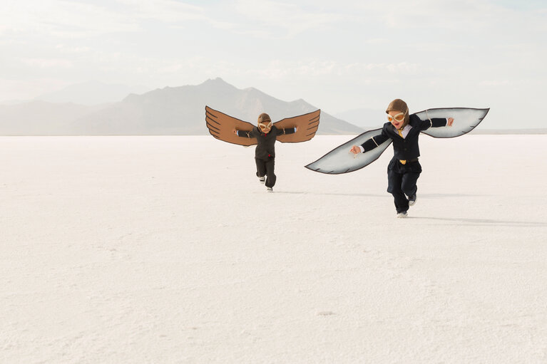 Young Business Boys Wearing Cardboard Wings Are Flying