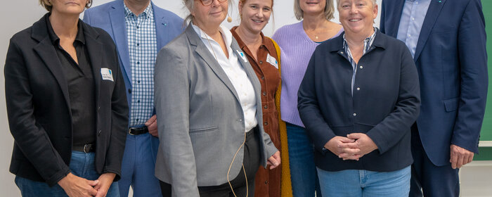 Sieben Personen stehen zusammen.