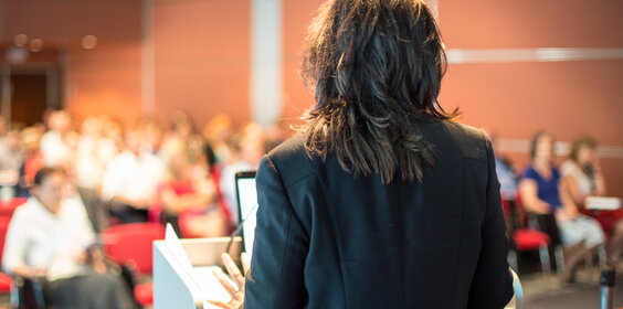 Female public speaker giving talk at Business Event.