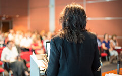 Female public speaker giving talk at Business Event.