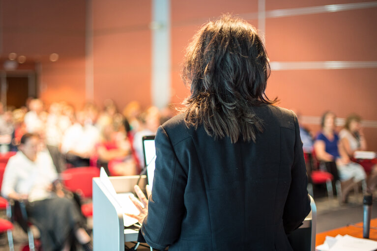 Female public speaker giving talk at Business Event.