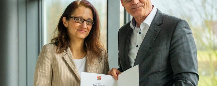 Eine Frau und ein Mann halten eine Urkunde