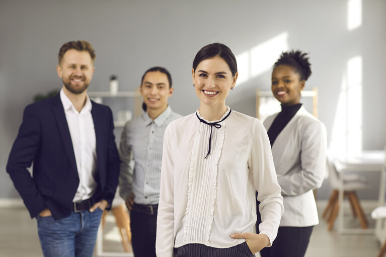 Portrait of happy beautiful business woman together with team of diverse employees