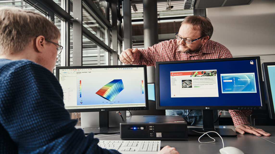 Professor und Student besprechen die Ergebnisse einer Simulation am Computer.