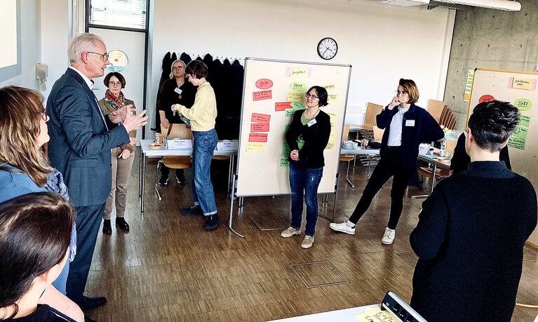 Frauen an Flipcharts sind im Gespräch mit einem Mann.