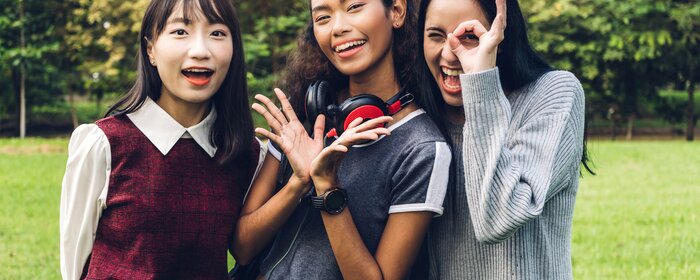 Drei Frauen stehen lachend beieinander.