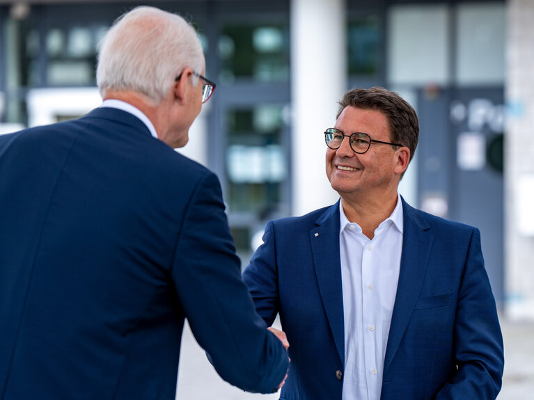 Zwei Männer reichen sich zur Gratulation die Hände.
