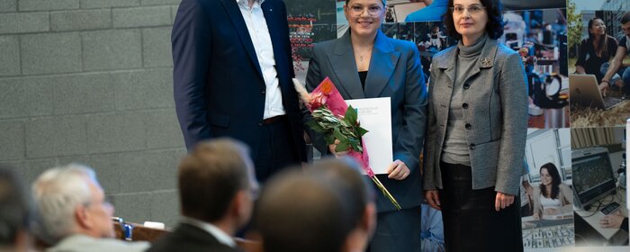 Ein Mann und zwei Frauen stehen auf der Bühne.
