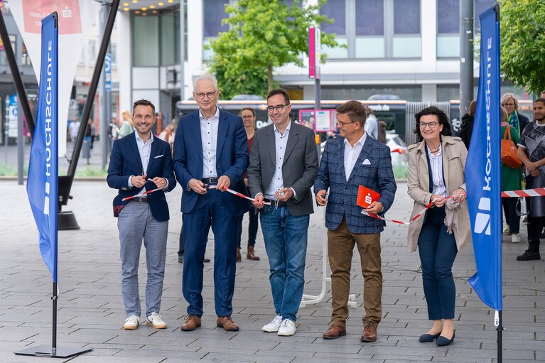Vier Männer und eine Frau stehen zusammen und zerschneiden das Eröffungsband.