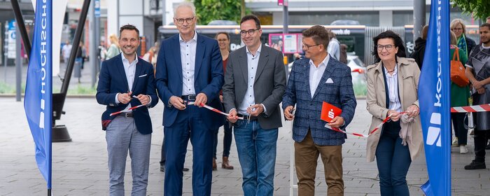 Vier Männer und eine Frau stehen zusammen und zerschneiden das Eröffungsband.