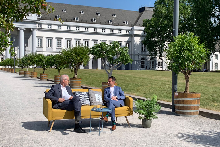 Zwei Männer auf einem gelben Sofa vor einem Schloss