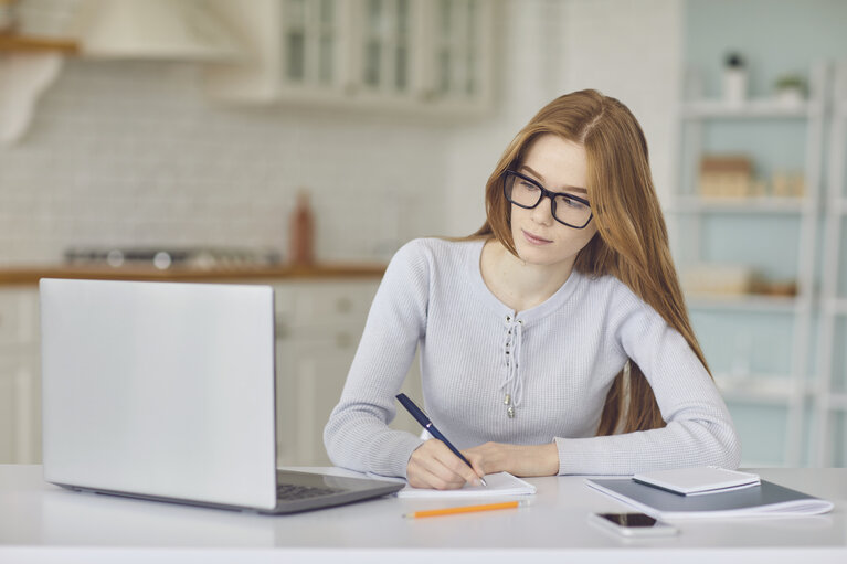 Online education. Girl in glasses studying using a laptop video call chat web camera watching college university at home.