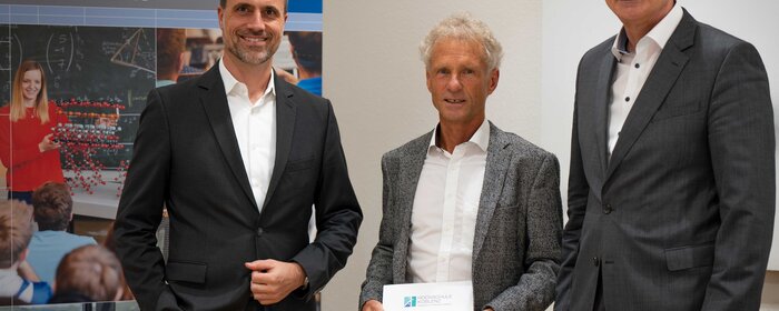 Drei Herren stehen zusammen. 