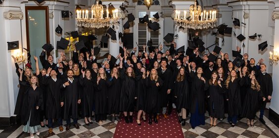 MBA-Absolvierende werfen ihre Hüte zur Feier des akademischen Abschlusses