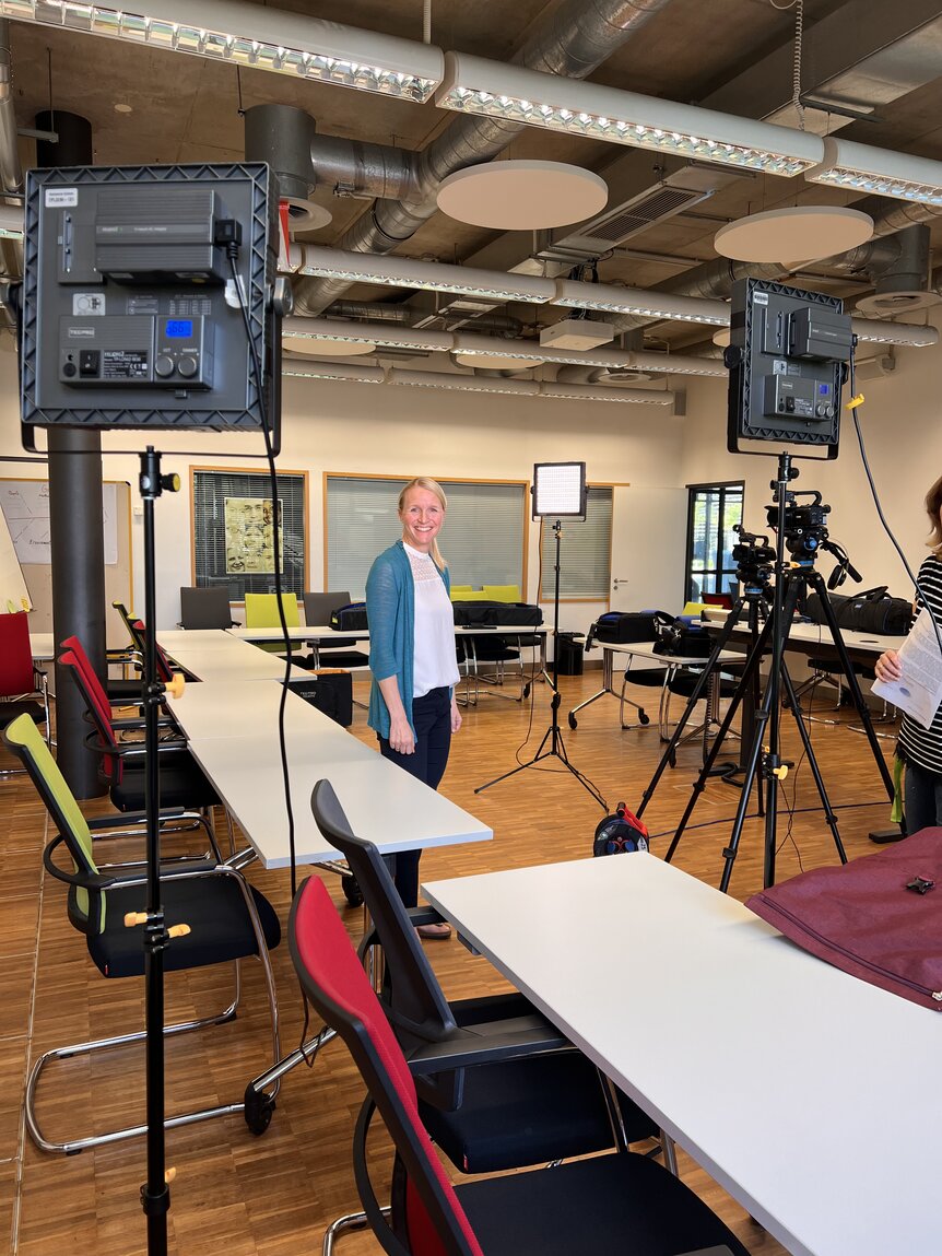 Das Bild zeigt einen Seminarraum. Darin aufgebaut ist ein Videoset mit Kameras und Licht. In der Mitte steht Prof. Dr. Mareike Heinzen. Die Kameras sind auf sie gerichtet.