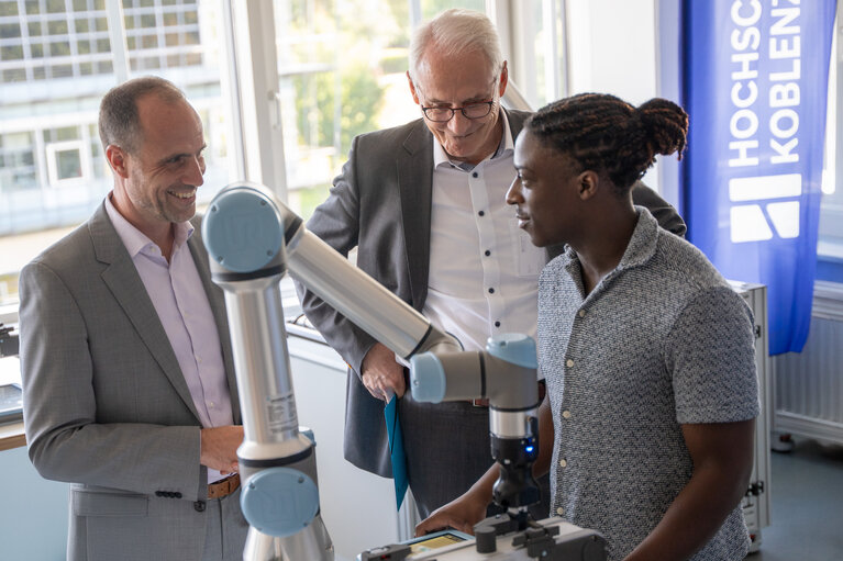 Drei Männer vor einem Robotermodell im Labor