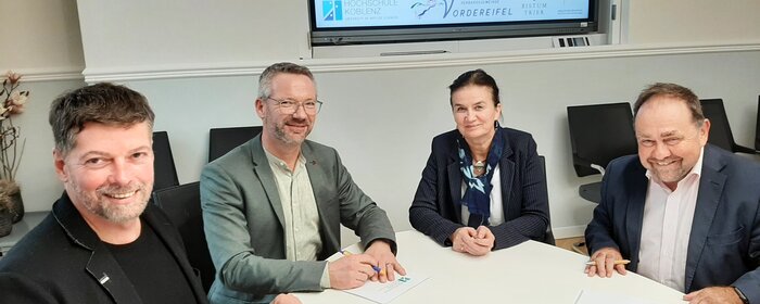 Vier Personen sitzen an einem Tisch. 