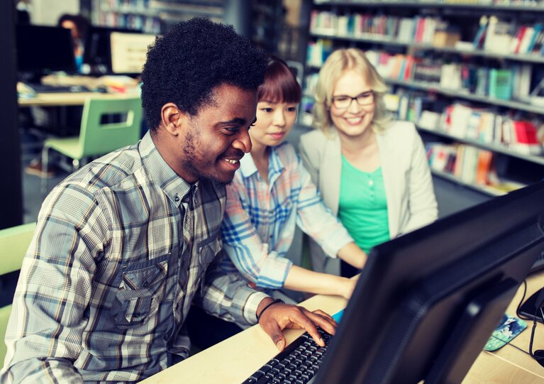 International Studierende am PC in einer Bibliothek