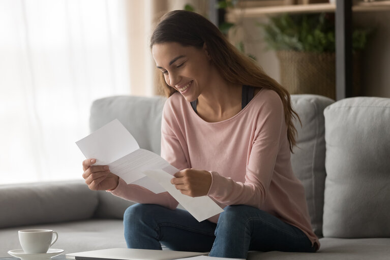 Happy woman read letter with loan approval sit on sofa