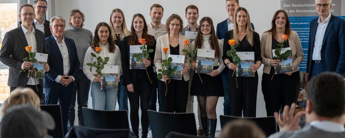 Eine Gruppe von Personen positioniert sich auf einer Bühne.