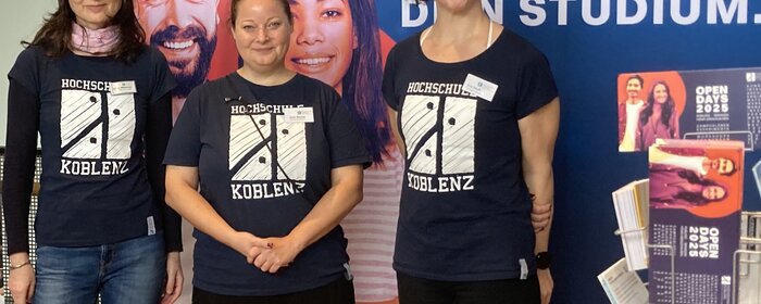 Drei Frauen stehen an einem Projektstand.