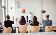 Studierende werfen einen Basketball, Football und Tennisball in die Luft