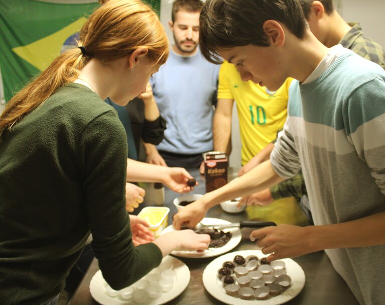 Erasmus-Studierende bereiten gemeinsam mit den Schülerinnen und Schülern des Franziskus Gymnasiums Nonnenwerth die brasilianische Süßspeise „Brigadeiro“ vor.