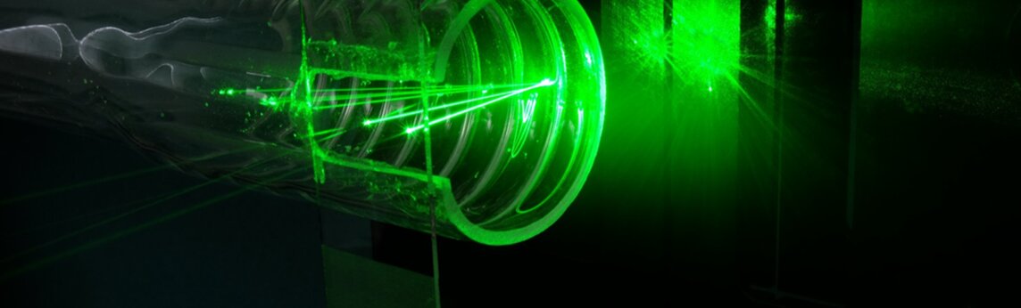 Foto grüner Laserstrahlen, die sich im Messpunkt am Strukturrohr kreuzen