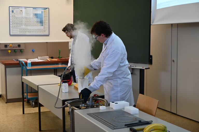 Zwei Männer im Chemiekittel führen Experimente vor.