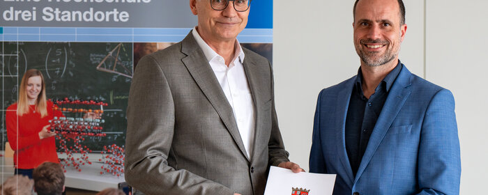 Zwei Männer stehen zusammen und halten ein Dokument in der Hand.