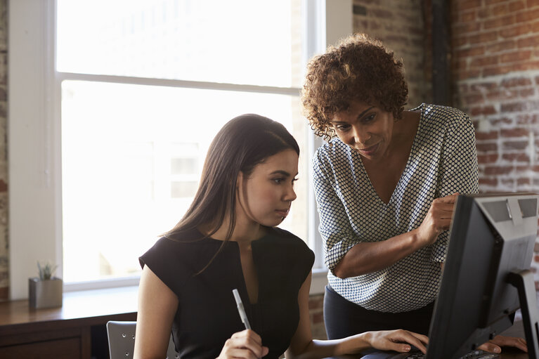 Two Businesswomen Working On Computer In Office