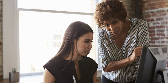 Two Businesswomen Working On Computer In Office