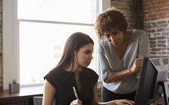 Two Businesswomen Working On Computer In Office