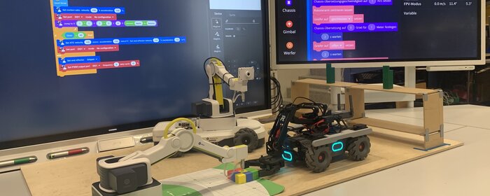 Das Bild zeigt einen Roboter vor einem Bildschirm. 